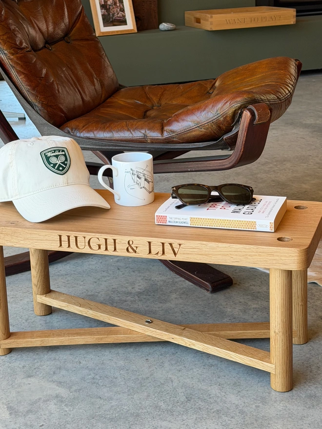 Oak swing seat on its legs used as a side table beside a leather chair, engraved with two names