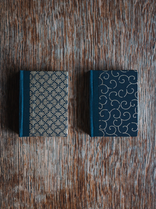 Two miniature hardback journals, with assorted black and gold printed covers