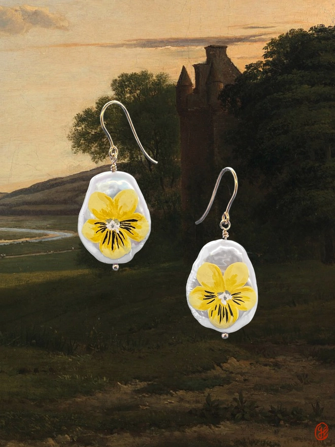 A pair of flat pear shaped pearl drop earrings, set in 9ct gold and painted with a yellow field pansy motif.