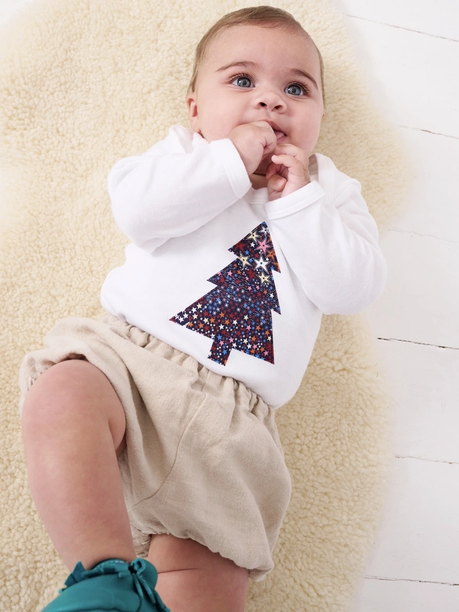 a baby wearing a christmas tree liberty starry print white bodysuit