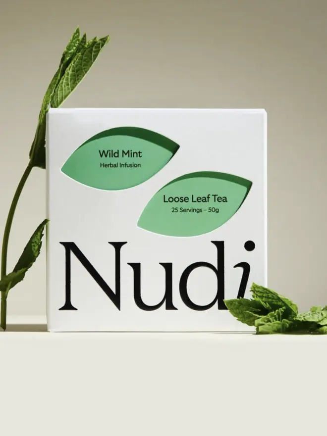 white box of mint team with green leaf design next to sprig of fresh mint