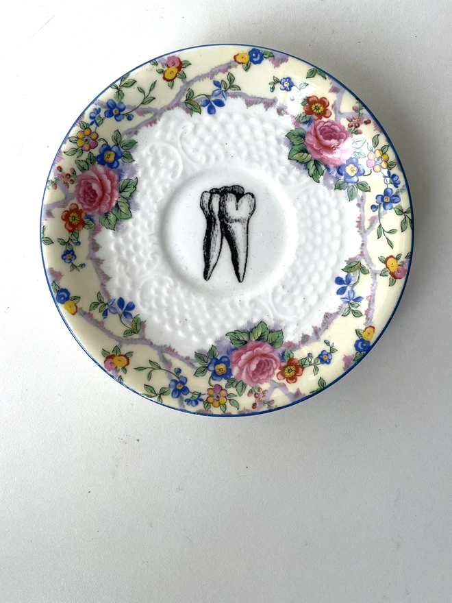 vintage plate with ornate border has a black and white image of a victorian molar tooth in the centre