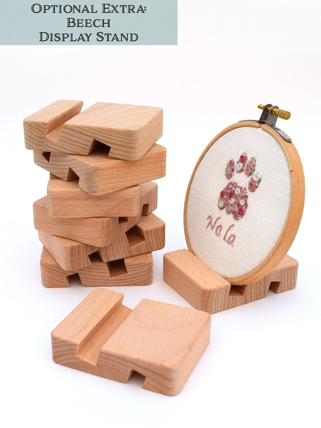 Wooden (Beech) Display Stand.  A stack of stands in the background.  Also an embroidered Pink Cat Paw in an embroidery hoop placed in the stand as an example of use.