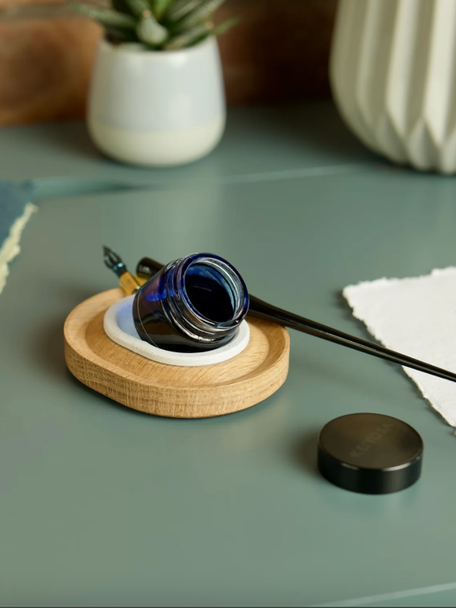 Versatilt Ink Stand. An ink stand in Marble White with a full pot of ink inside, shown tilted.