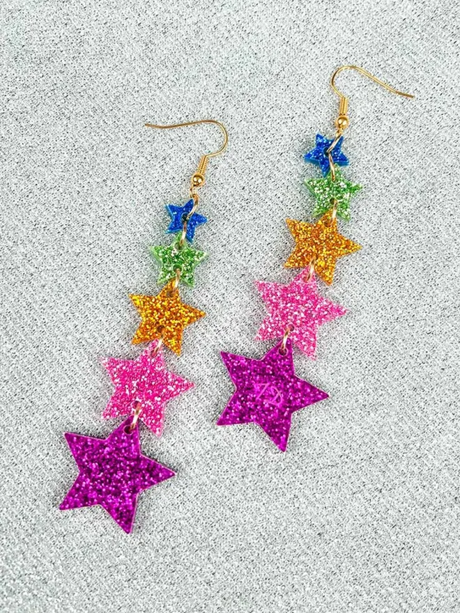 Multi coloured, glittery Super Star Earrings on a background