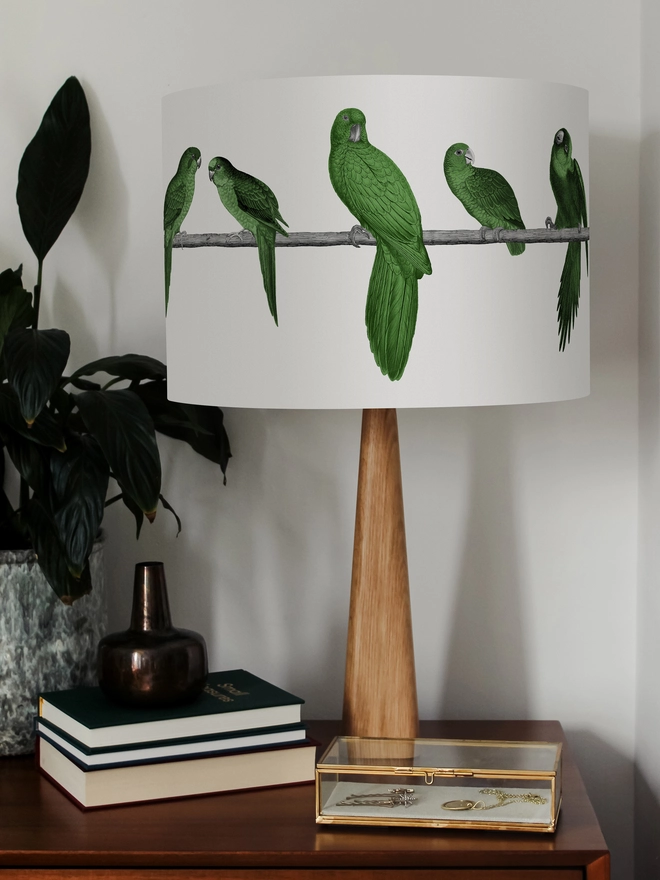 A colourful lampshade featuring a lively group of green parrots in a tropical jungle-inspired design, bringing a playful touch to home interiors.