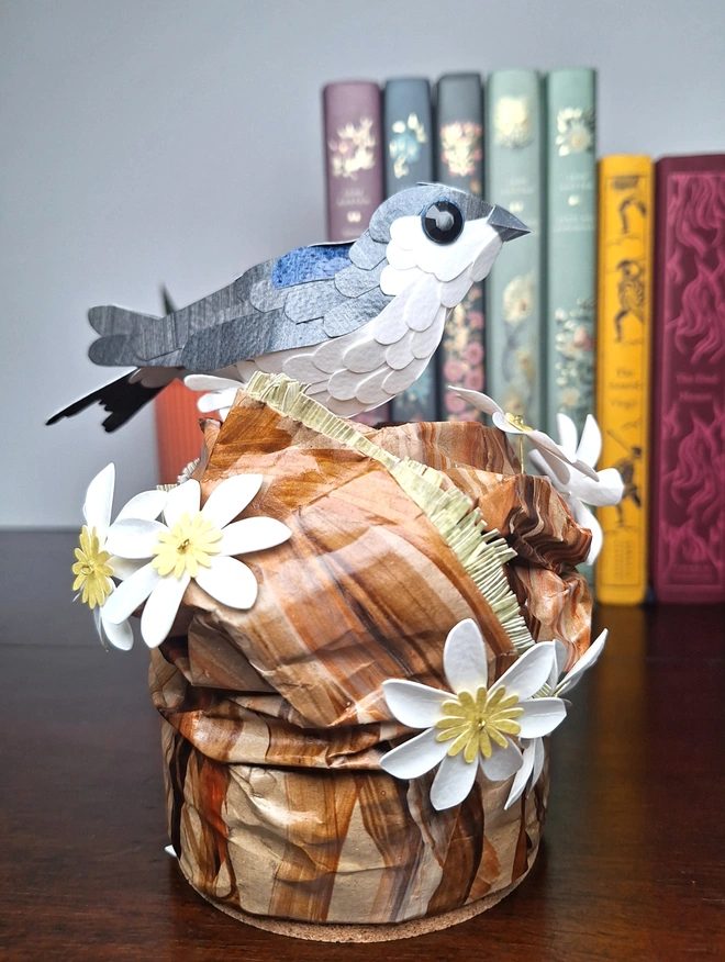 Housemartin sculpture. A handmade paper sculpture depicting a housemartin bird perched on a tree stump.