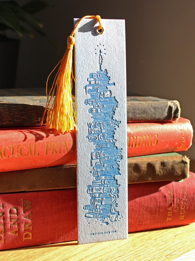 Stack of books letterpress bookmark leaning on books