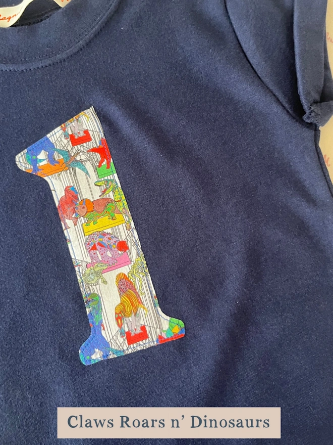 A navy birthday t-shirt with a number 3 cut from liberty dinosaur print on the front