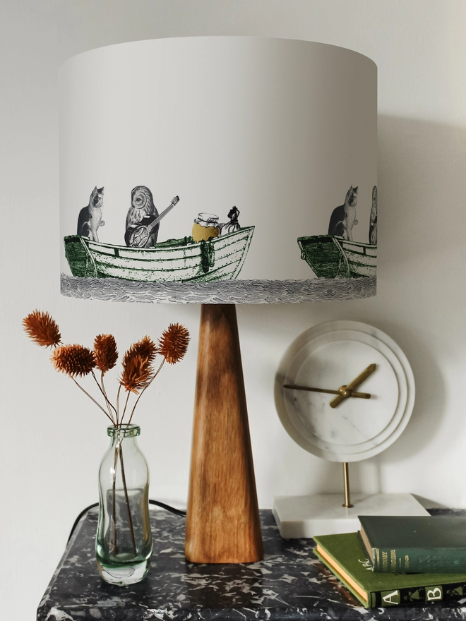 Drum Lampshade featuring the Owl and the Pussycat on a wooden base on a shelf with books and ornaments