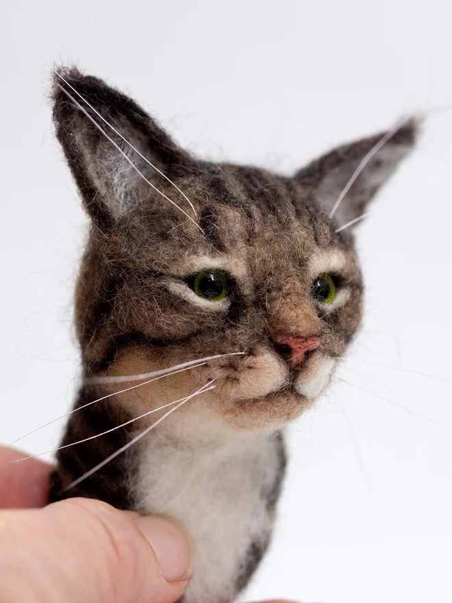 A handmade needlefelted tabby cat portrait being held by the artist Laura Cronin aka Bumble & Earwig 