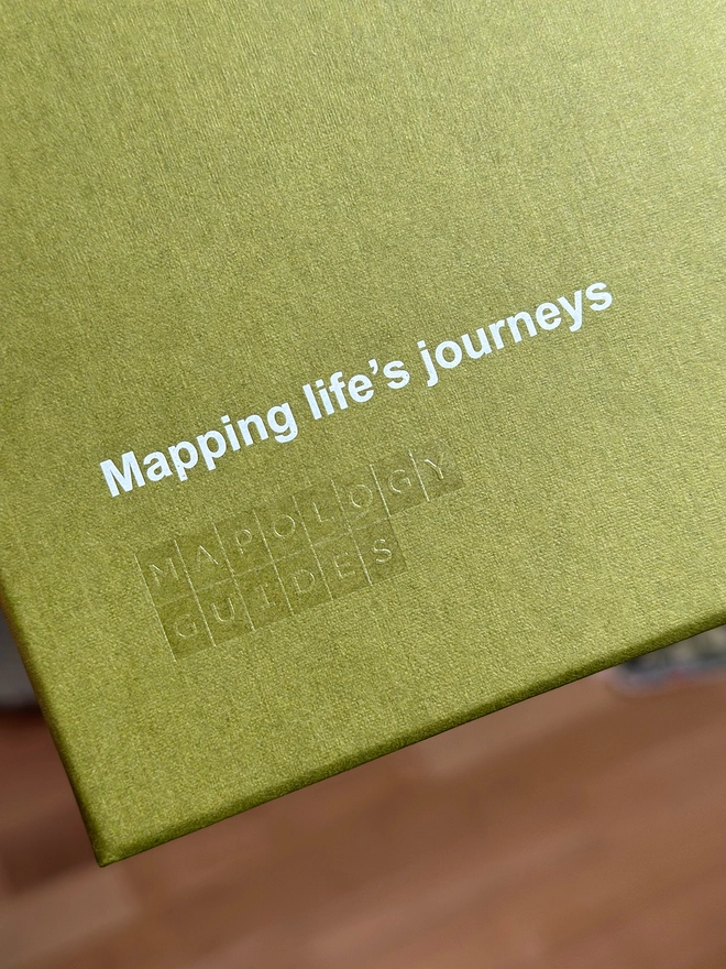 close up of gift box with hot-foil logo. Reads Mapping life's journeys