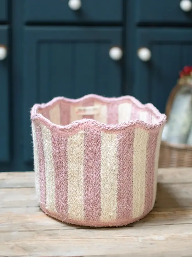 Dusty Pink stripy scalloped organic jute basket on a kitchen table top. . 