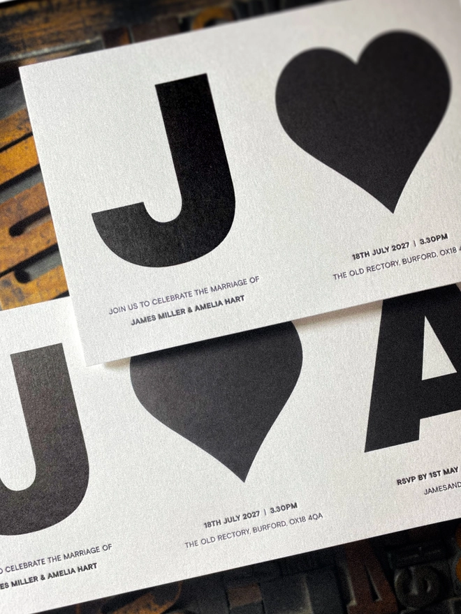 Close-up of luxury Amour Mono concertina wedding invitation showing personalised initials, heart, date and venue details printed in crisp black ink on Pristine White Colorplan.