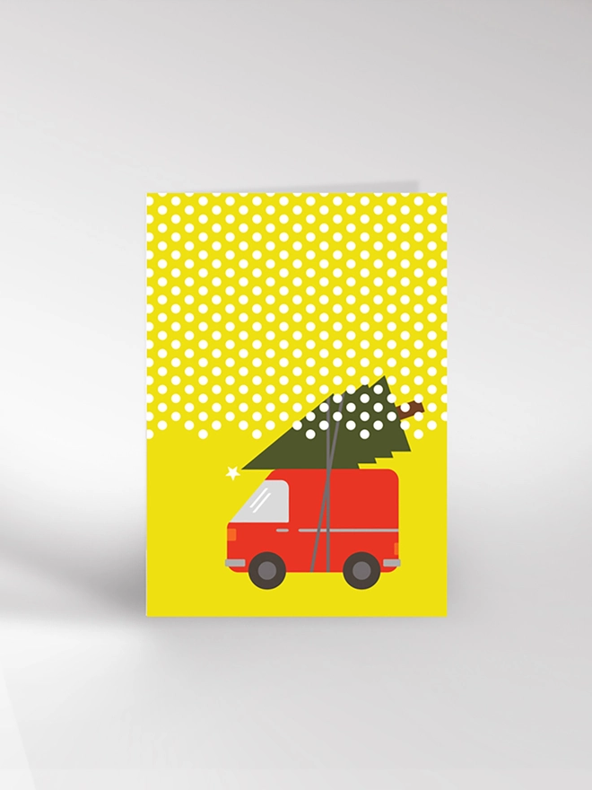 Christmas card illustrating a red van with a Christmas tree strapped to the roof