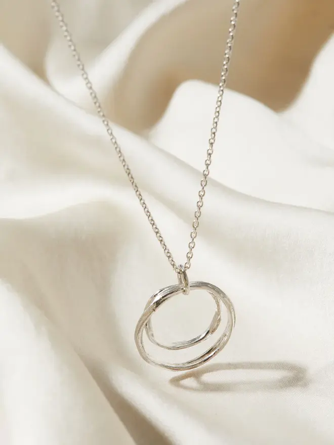 Sterling Silver Double Circle 'You and Me' Necklace draped over a silk material