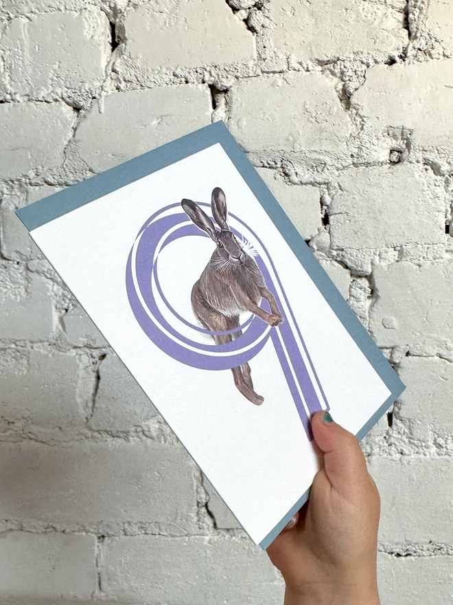white card with a big purple number 9 and a hare illustration with a blue envelope