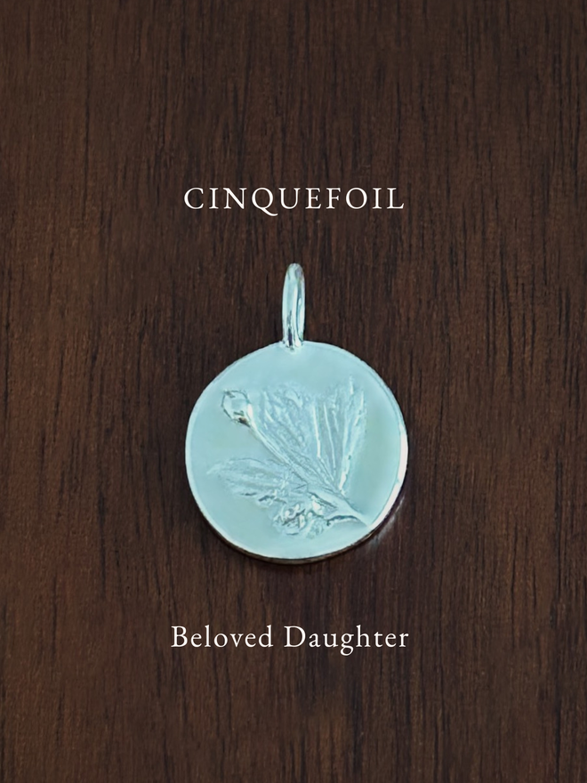 Sterling Silver Cinquefoil Coin Charm on a dark background with the language of flowers meaning, beloved daughter