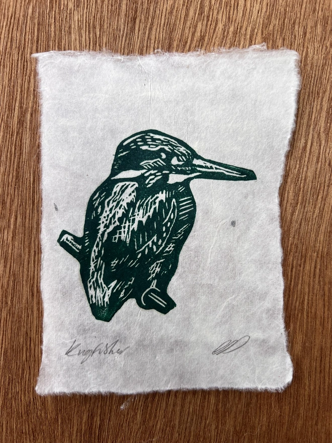 Hand-printed green kingfisher lino print on natural handmade paper, featuring a bold graphic illustration of a kingfisher.