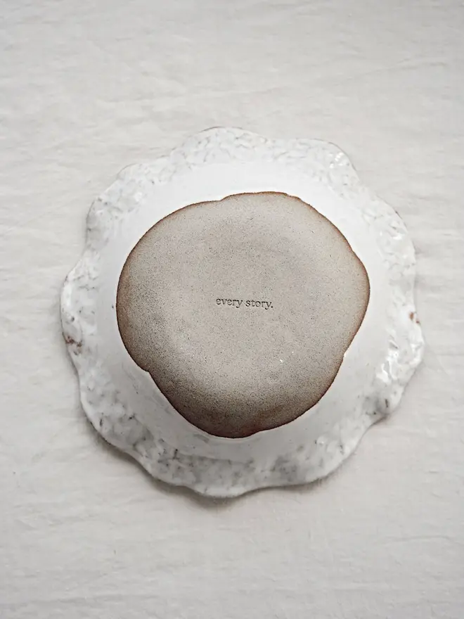 Dapple Stoneware Cereal & Salad Bowl, the flip side of the bowl, placed on a table cloth. 