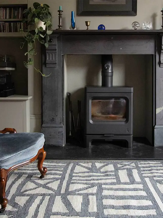 Tudor Flatweave Rug, a colourful rug in a living room. It is surrounded by other household items. 