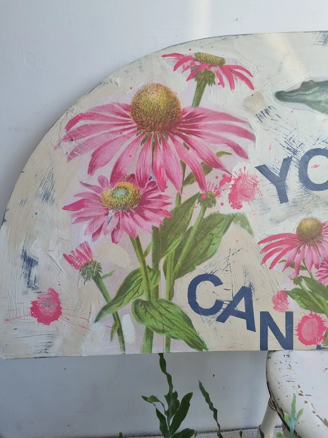 Art panel in a crescent shape made from a piece of vintage table top. Decorated with decoupage images of a man holding a crocodile aloft and pink flowers. The text reads 'you can do hard things'. The colours are cream with splashes of pink