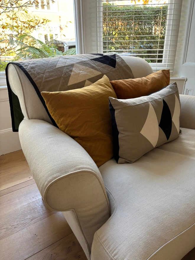 Flow Taupe Linen Throw Quilt. Throw quilt draped on armchair.