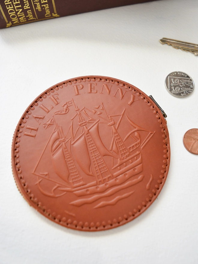 a tan leather half penny coin purse with a ship embossed 