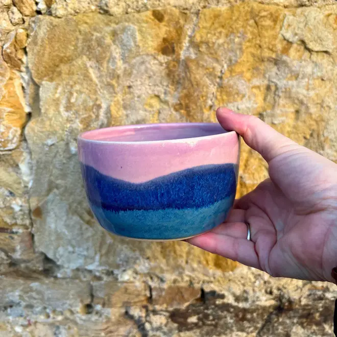 Landscape Small Bowl, a colourful bowl held against a brick backdrop. 