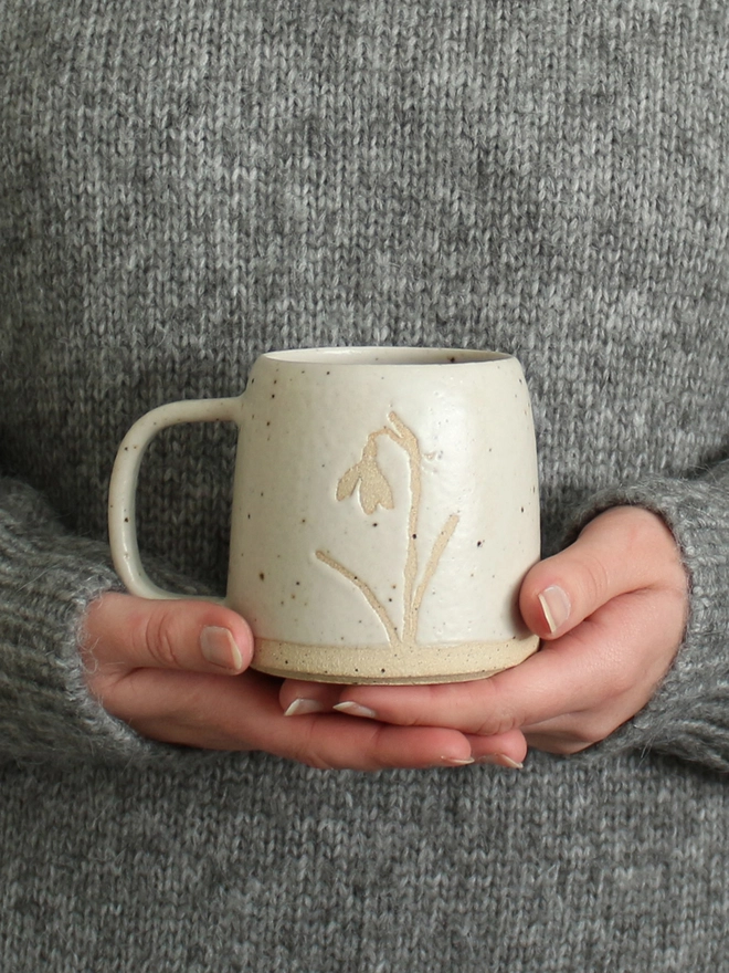 Hands holding snowdrop mug