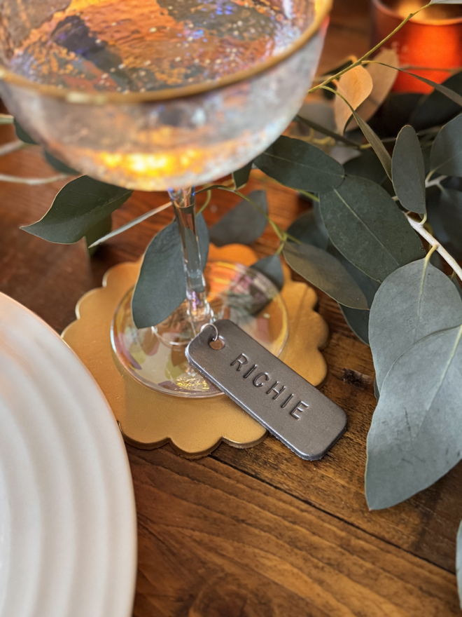 pewter leather glass charm on a scalloped gold leather coaster