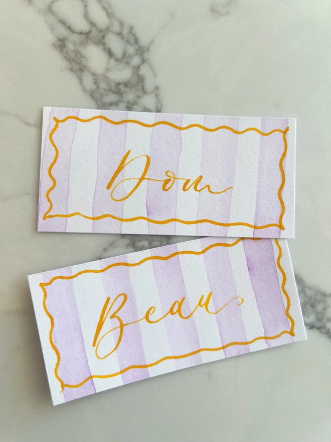 Personalised calligraphy event place cards, purple striped coloured place cards with orange calligraphy name
