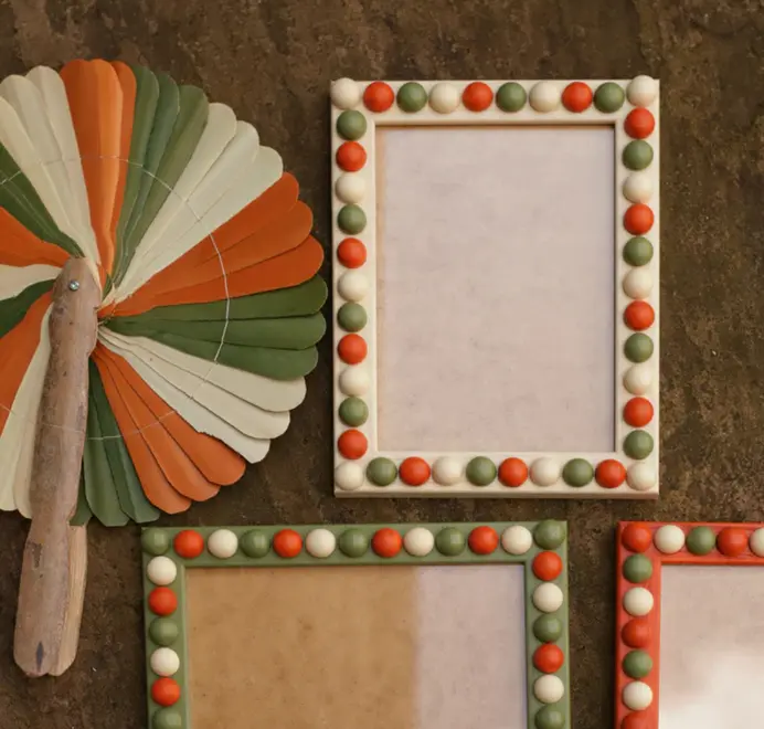 white orange and green bobbin frames next tor hand fan in matching colours