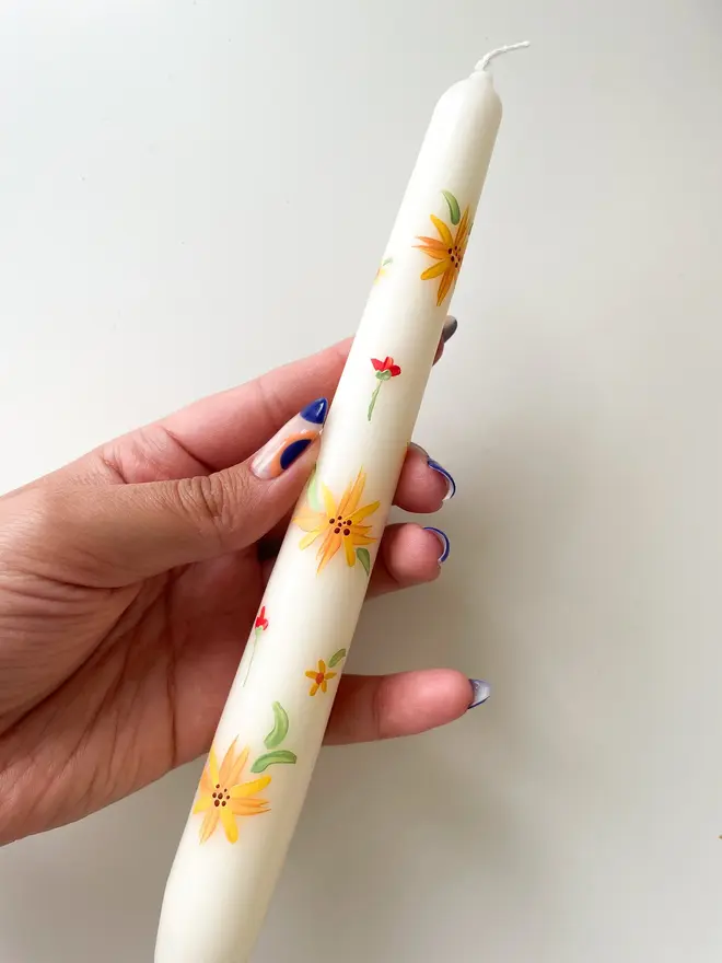 Blooming For You & Spring Bound Hand Painted Candle, a taper candle against a white surface. The floral design can be seen wrapping around them. 