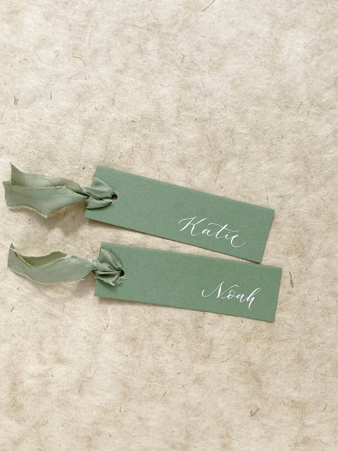 sage green calligraphy wedding place cards. green wedding place cards with silk ribbon and white calligraphy.