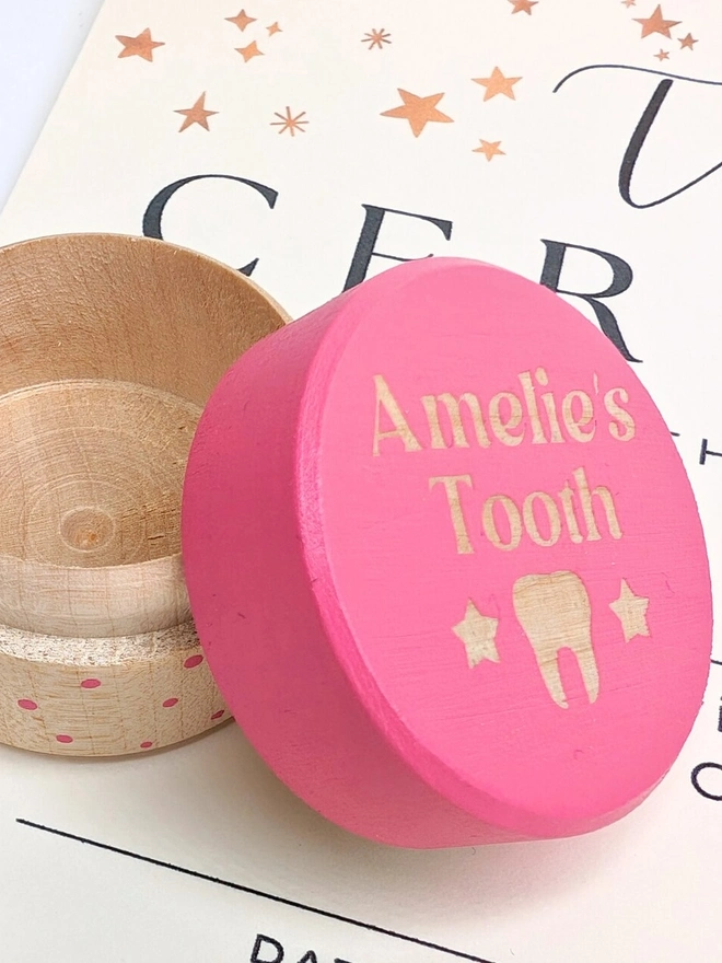 personalised wooden tooth fairy box. a round wooden box with a pink painted lid and personalised text.