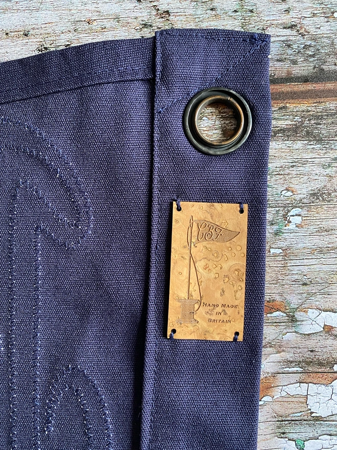 Detail of the back of a navy 'Better together' pennant flag. This shows the stitch work on the back with a hanging eyelet and a cork label.