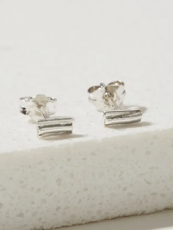 Two Silver Ripple Stud Earrings on a marble slab