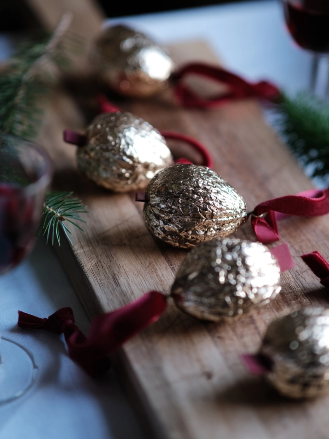 Handmade walnut Christmas ornament with delicate gold gilding, showing the natural shape and grain of the wood. A traditional, nostalgic Christmas tree decoration with timeless old-fashioned charm.