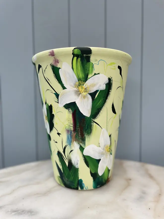 Hand-painted terracotta plant pot featuring white clematis flowers on a pale green background  