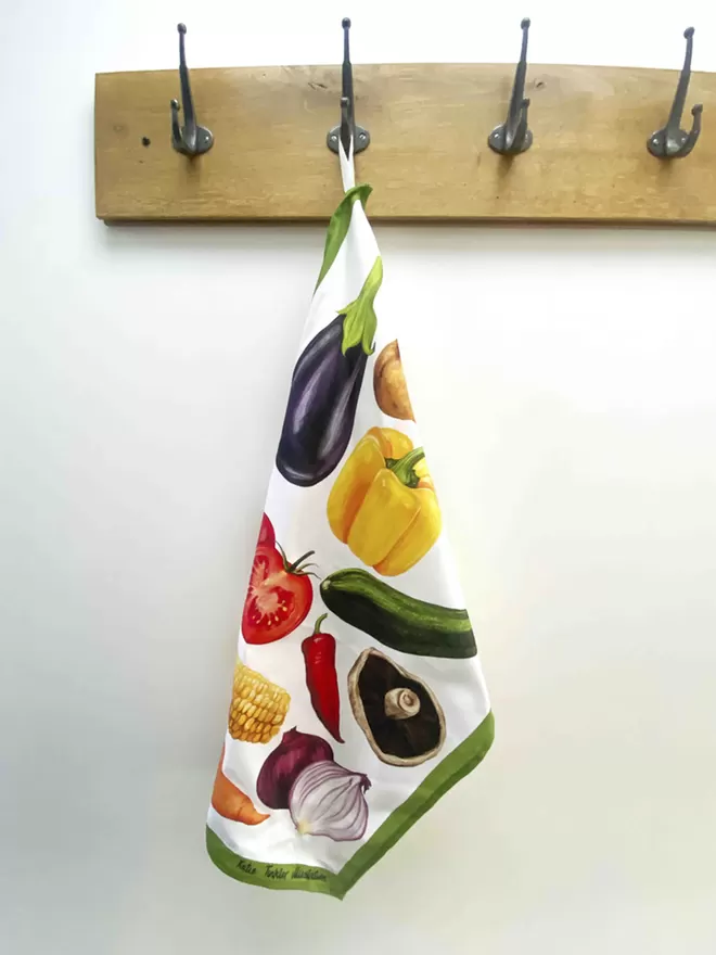 A vegetable themed tea towel hanging on a coat hook