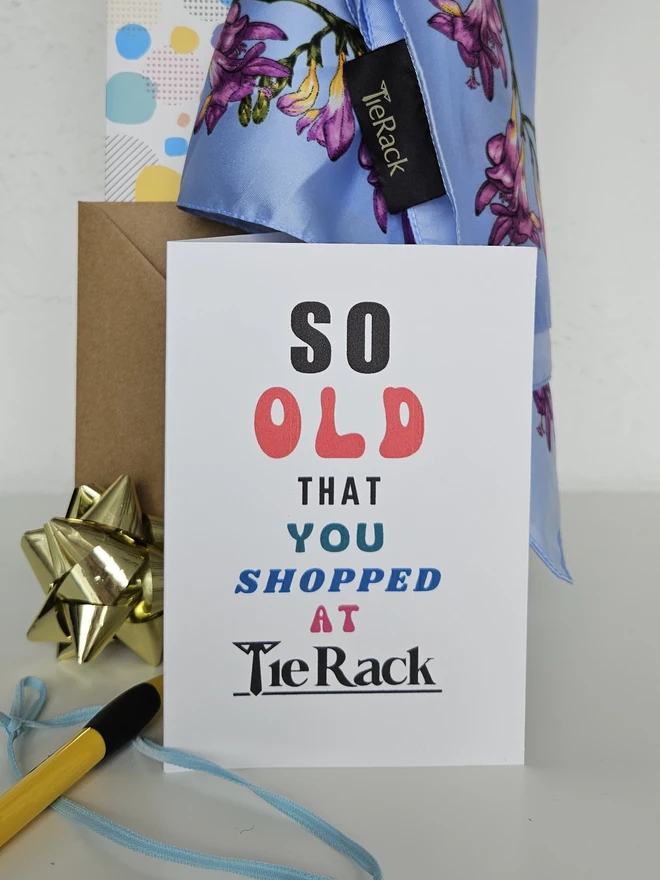 A photograph of the front of a humorous A6 greeting card illustrated using brightly coloured text and the retro shop logo. The text says so old you shopped at Tie Rack