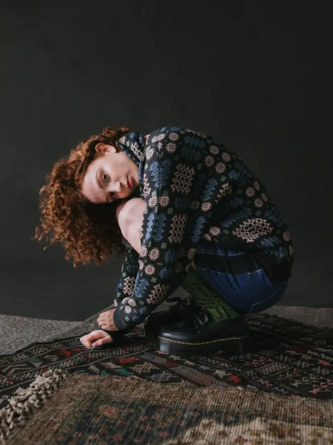 Model wearing pieces from MABLI's 'Carthen' collection, featuring the Carthen Cardigan in the vibrant 'Emeralds' colour-way. The design showcases bold, colourful patterns inspired by traditional Welsh blanket tapestry.