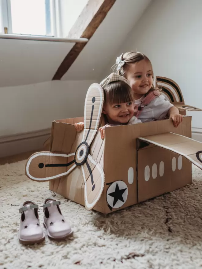 little girls playing in a cardboard airplane wearing Pip and Henry lilac T bar shoes
