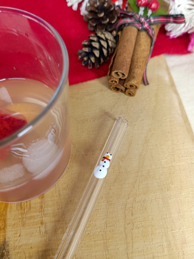 snowman straw laid next to a glass on a christmas layout