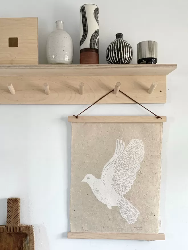 hang with bird print by Rosanna Morris. hanging from a Rack with ceramic vases on top.