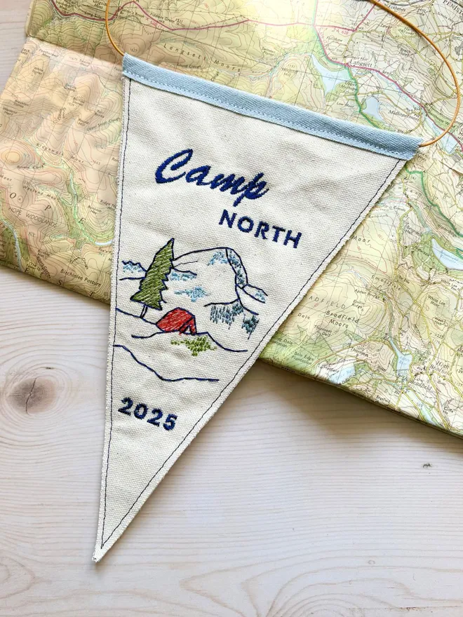 Embroidered mini camp pennant flag on a vintage map