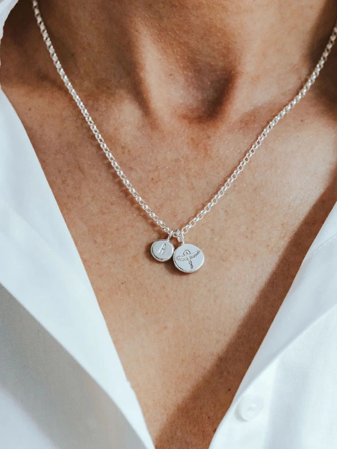 A woman wearing a Sterling silver Phoenix Pebble Necklace with a letter charm