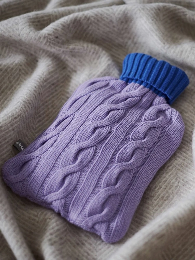 Cashmere Hot Water Bottle Cover, a colourful water bottle sitting on a blanket. 
