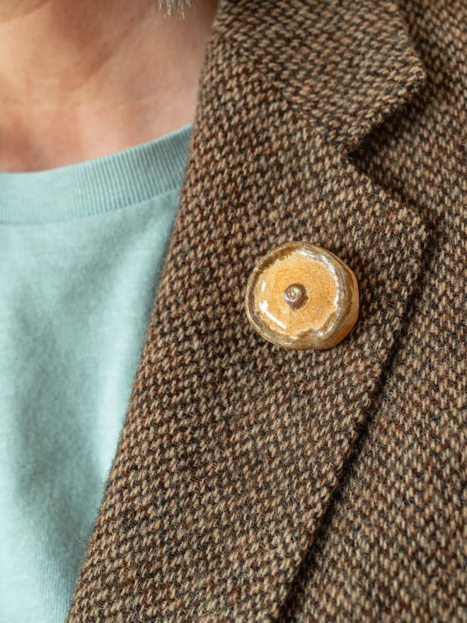 ceramic pastry pin badges. a ceramic scotch pie badge on a coat lapel.